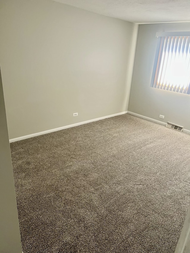 empty room featuring visible vents, baseboards, carpet floors, and a textured ceiling