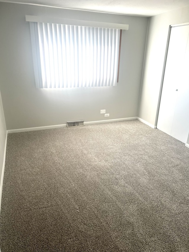 carpeted spare room with baseboards and visible vents