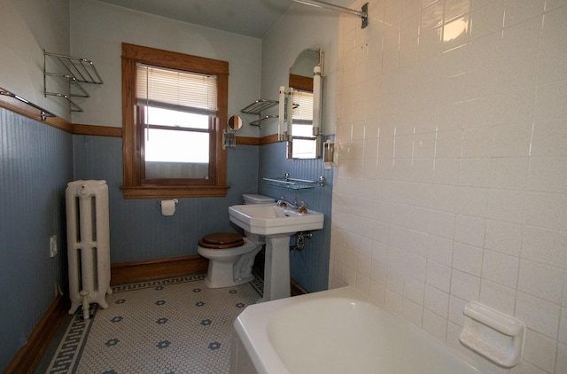 bathroom featuring tile patterned floors, sink, toilet, tile walls, and radiator heating unit