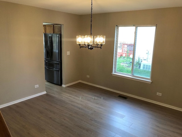 unfurnished dining area with dark wood-type flooring and a chandelier