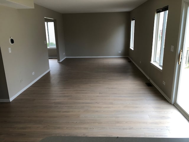 unfurnished room featuring a wealth of natural light and dark hardwood / wood-style floors