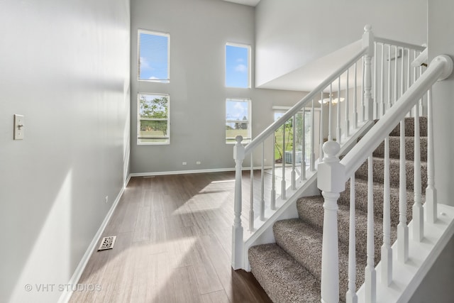 staircase featuring a high ceiling, an inviting chandelier, and hardwood / wood-style floors