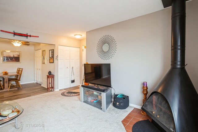 living room with ceiling fan, dark hardwood / wood-style flooring, and a wood stove