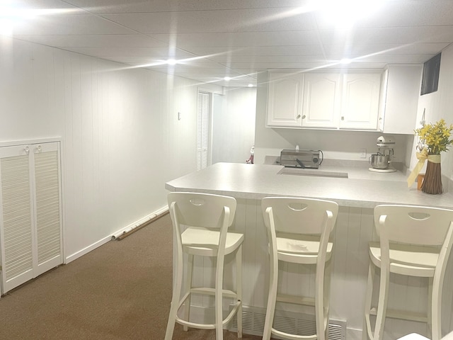 kitchen with kitchen peninsula, white cabinetry, and carpet floors