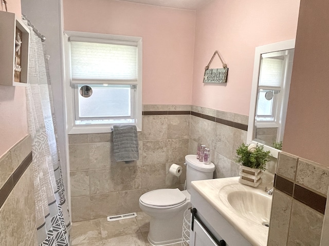 bathroom with tile patterned flooring, vanity, toilet, and tile walls