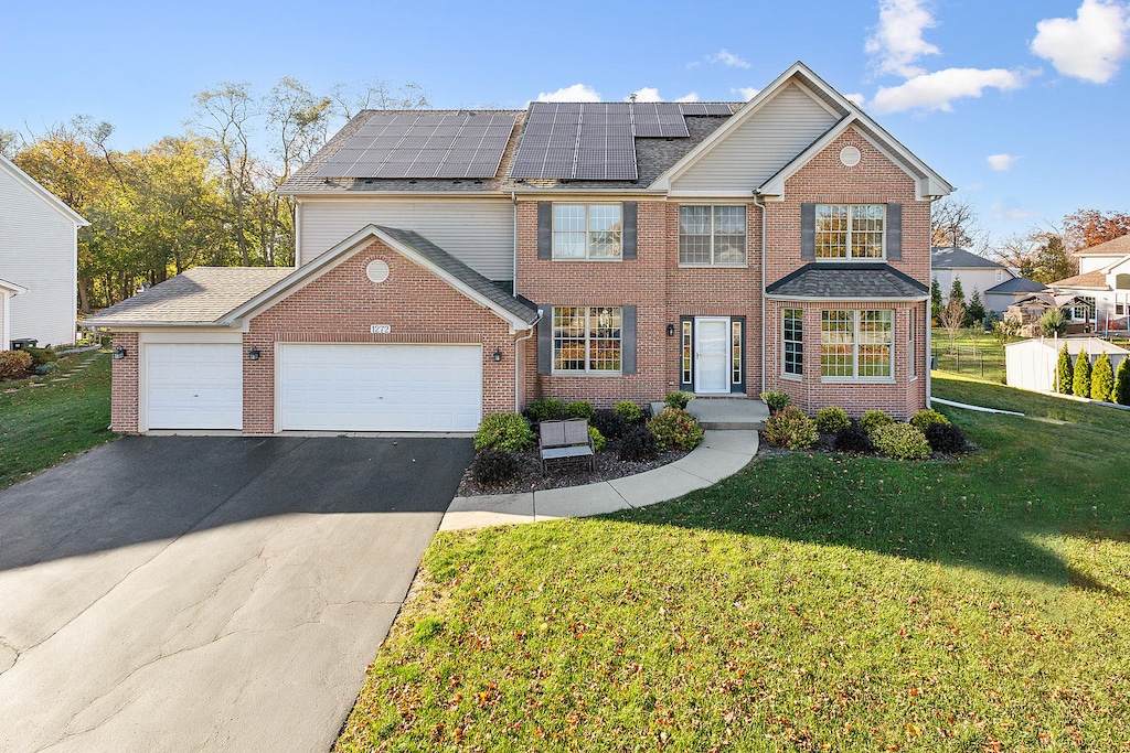 front of property with a front yard, solar panels, and a garage