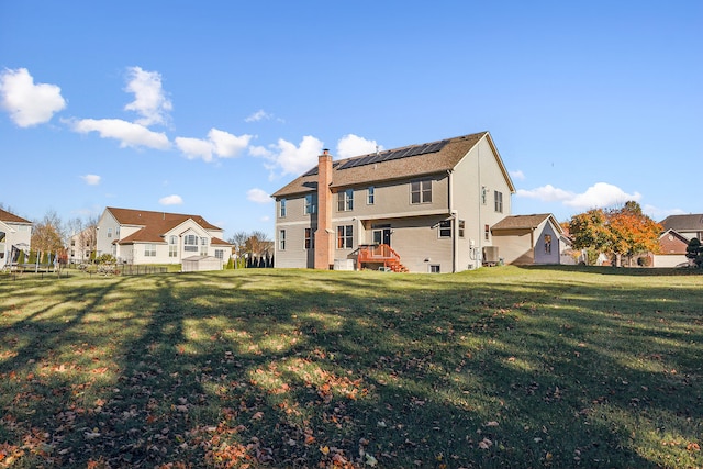 back of house featuring a lawn, solar panels, and cooling unit