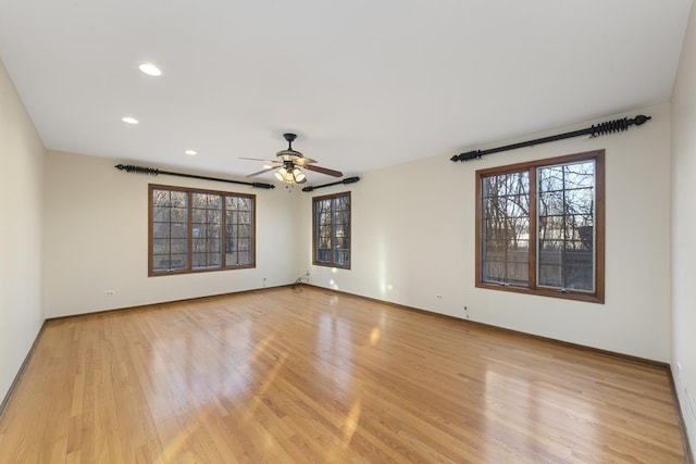 spare room with ceiling fan, a wealth of natural light, and light hardwood / wood-style floors