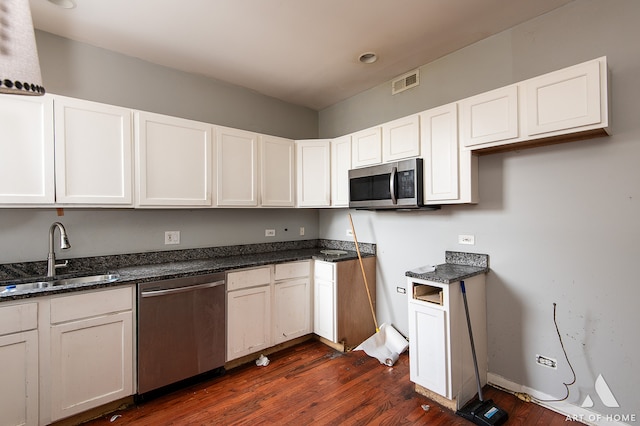 kitchen featuring white cabinetry, sink, appliances with stainless steel finishes, dark stone counters, and dark hardwood / wood-style flooring