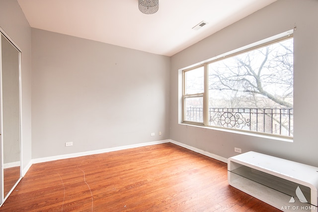 unfurnished bedroom with hardwood / wood-style flooring, multiple windows, and a closet