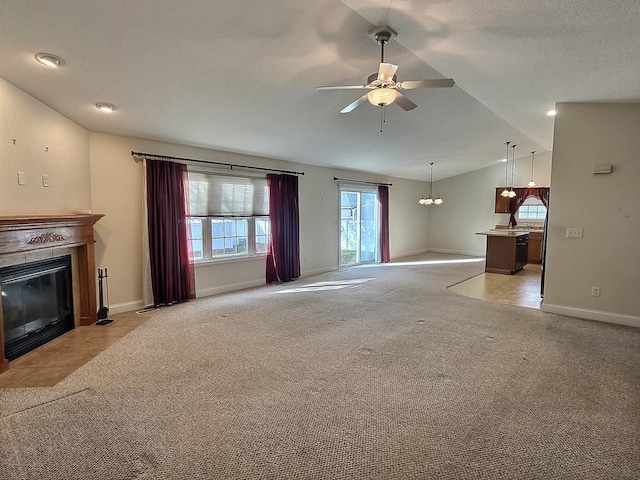 unfurnished living room with light carpet, ceiling fan with notable chandelier, and vaulted ceiling