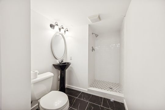 bathroom with toilet and tiled shower