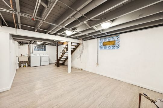 basement with washing machine and clothes dryer, sink, and hardwood / wood-style floors