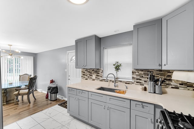 kitchen with stainless steel stove, sink, a notable chandelier, and a healthy amount of sunlight