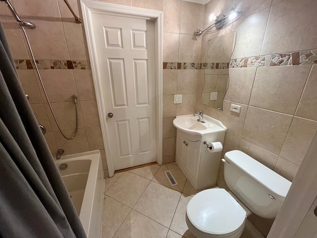 full bathroom with shower / bath combination with curtain, vanity, tile patterned floors, toilet, and tile walls