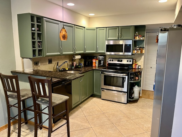 kitchen with green cabinetry, stainless steel appliances, dark stone counters, and sink