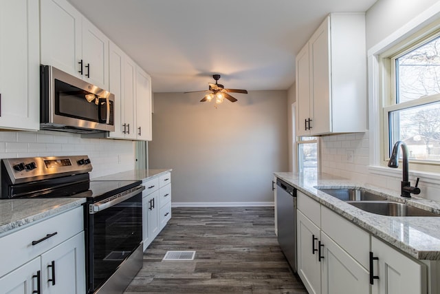 kitchen featuring sink, appliances with stainless steel finishes, light stone counters, white cabinets, and dark hardwood / wood-style flooring