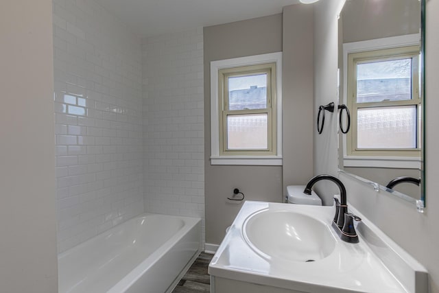 bathroom featuring hardwood / wood-style flooring, a healthy amount of sunlight, tiled shower / bath combo, and vanity