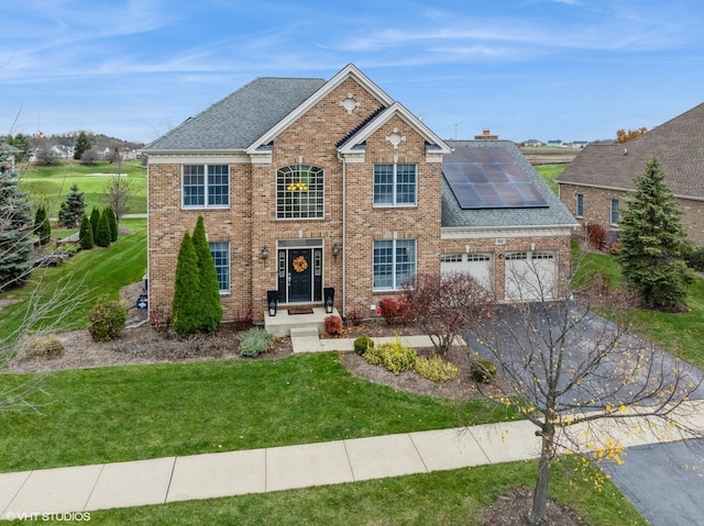 view of front of house with a front lawn, a garage, and solar panels