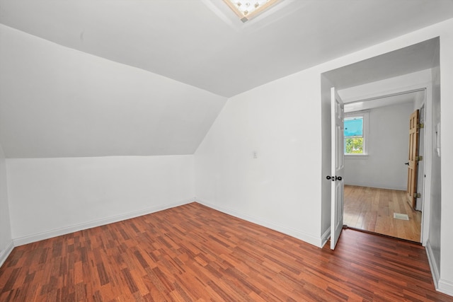 bonus room with dark wood-type flooring and lofted ceiling