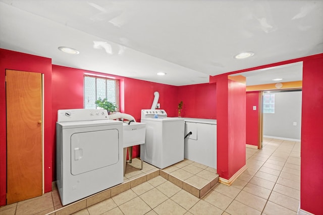 washroom featuring light tile patterned floors, sink, washer and dryer, and a healthy amount of sunlight