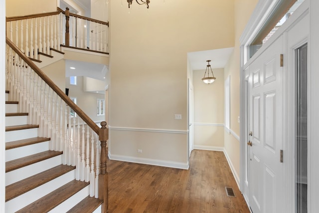 foyer entrance featuring a towering ceiling and wood-type flooring