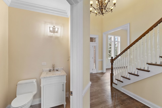 entrance foyer featuring crown molding, sink, dark wood-type flooring, and a notable chandelier