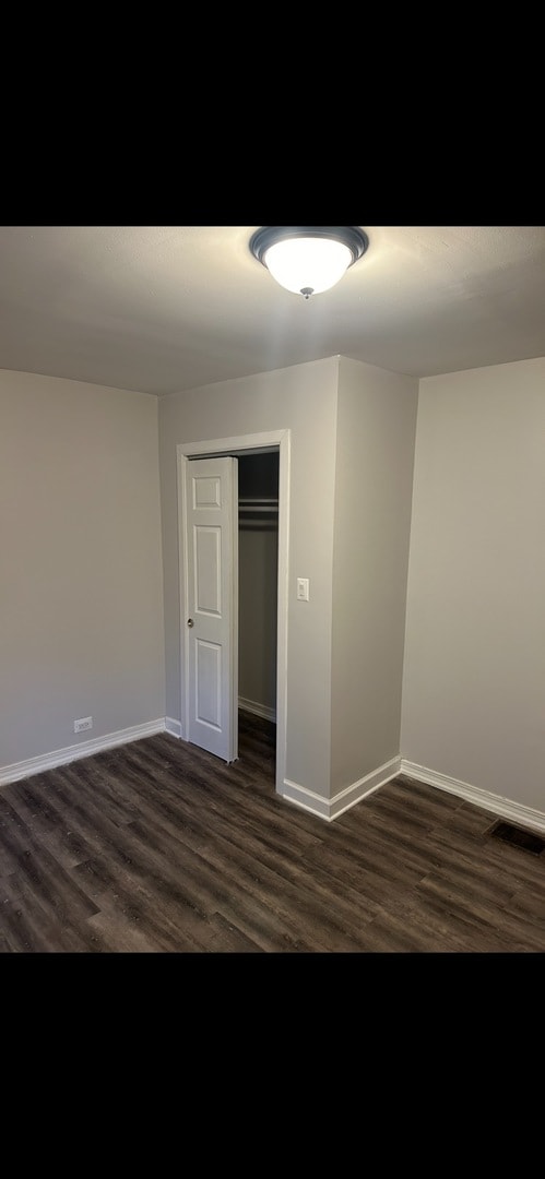 unfurnished bedroom featuring dark hardwood / wood-style flooring and a closet