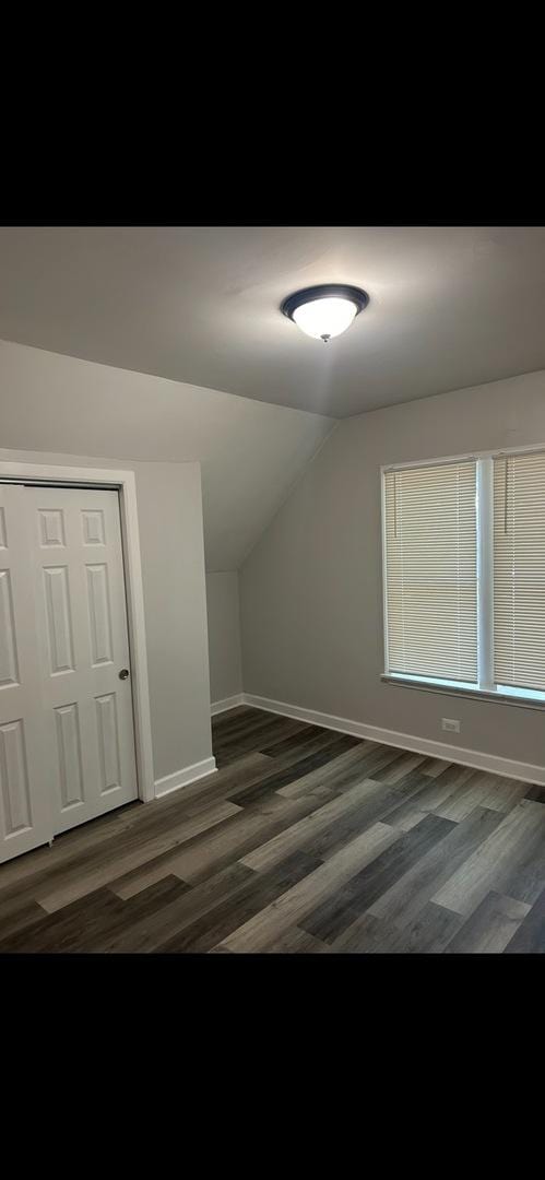 additional living space featuring baseboards, lofted ceiling, and wood finished floors