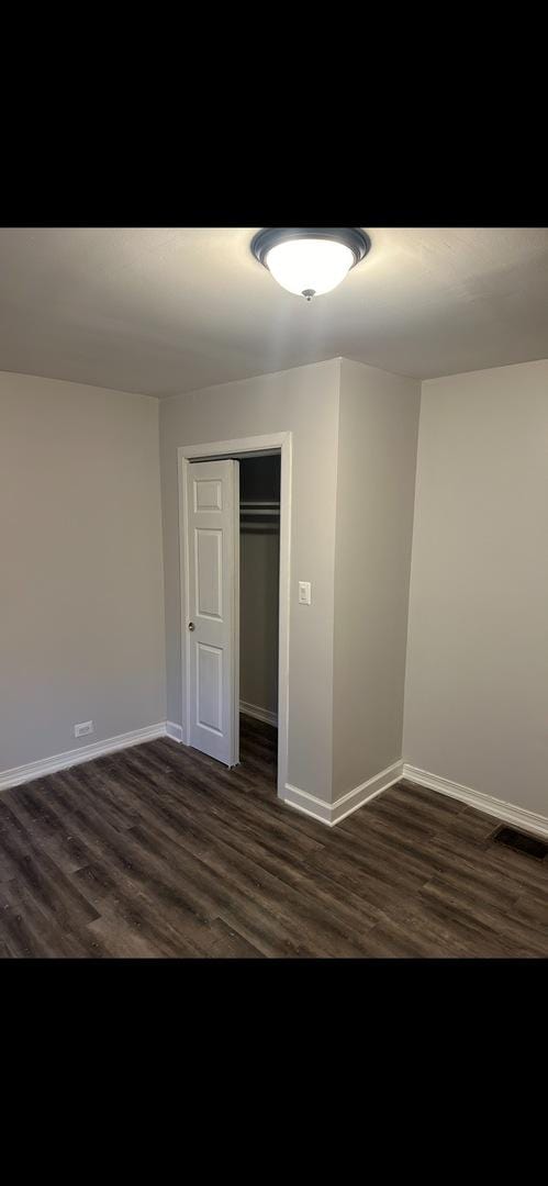 interior space featuring dark wood-type flooring, visible vents, baseboards, and a closet