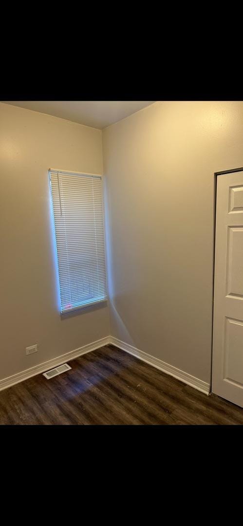 spare room featuring dark wood-style floors, baseboards, and visible vents