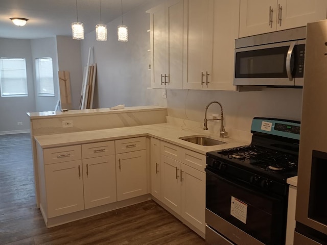 kitchen featuring white cabinets, a peninsula, stainless steel microwave, gas stove, and a sink