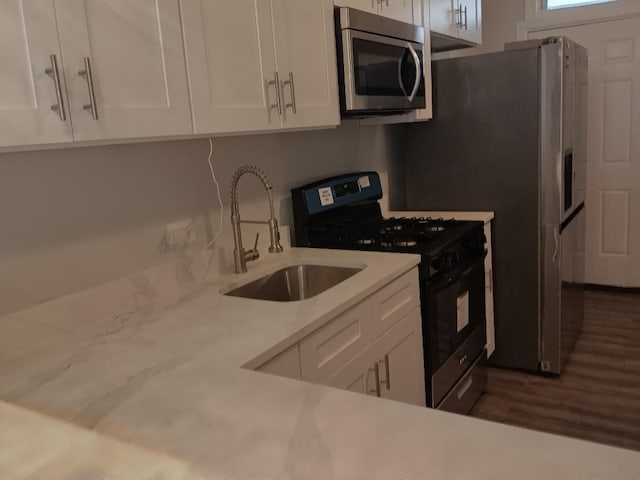 kitchen with white cabinetry, light countertops, stainless steel microwave, a sink, and black gas range oven