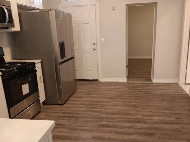 kitchen featuring light countertops, white cabinetry, appliances with stainless steel finishes, baseboards, and dark wood-type flooring
