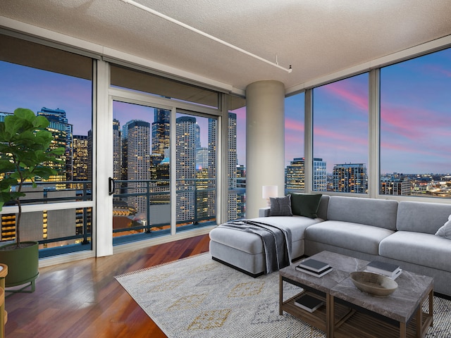 living room featuring a wall of windows, dark wood-type flooring, and a textured ceiling