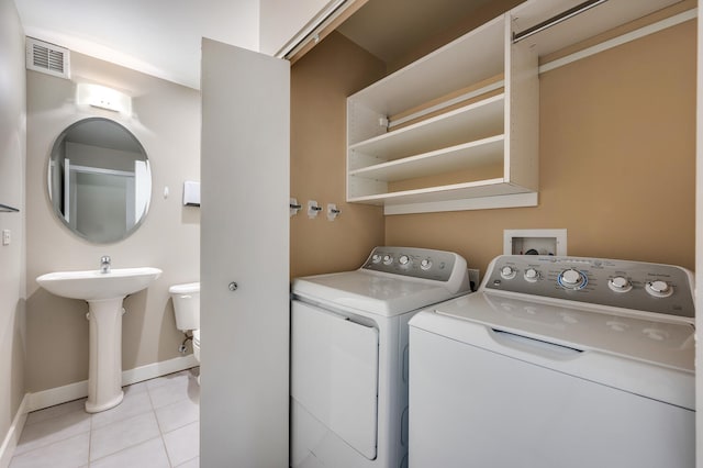 laundry area with washing machine and dryer, sink, and light tile patterned floors