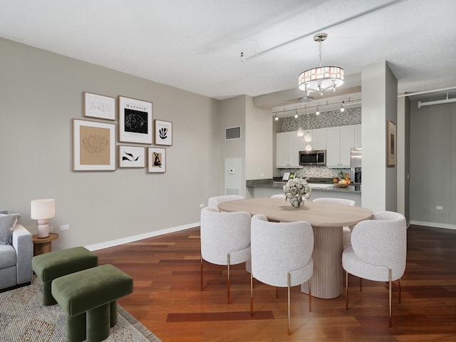 dining space featuring an inviting chandelier, dark hardwood / wood-style floors, and track lighting