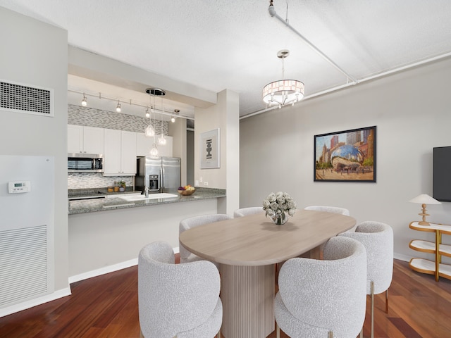 dining space featuring dark hardwood / wood-style floors, rail lighting, and an inviting chandelier