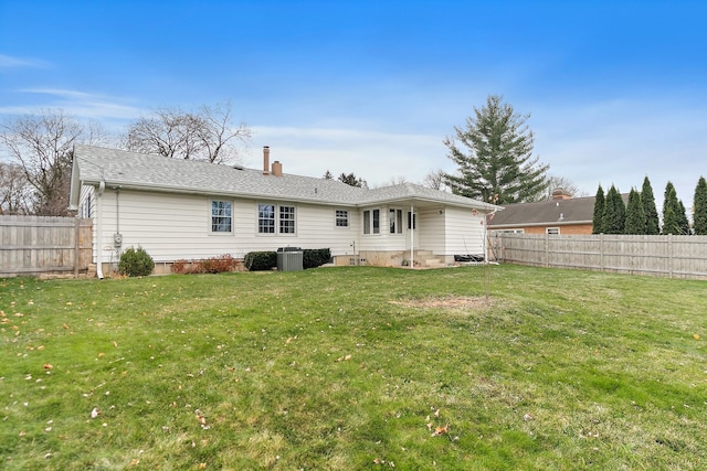 rear view of property with central AC and a yard