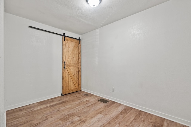 spare room featuring light hardwood / wood-style floors and a barn door