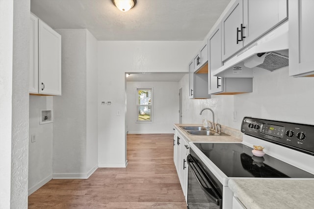 kitchen with white cabinets, black electric range oven, light hardwood / wood-style floors, and sink