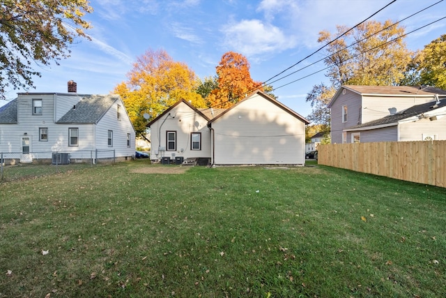 back of house with central air condition unit and a lawn