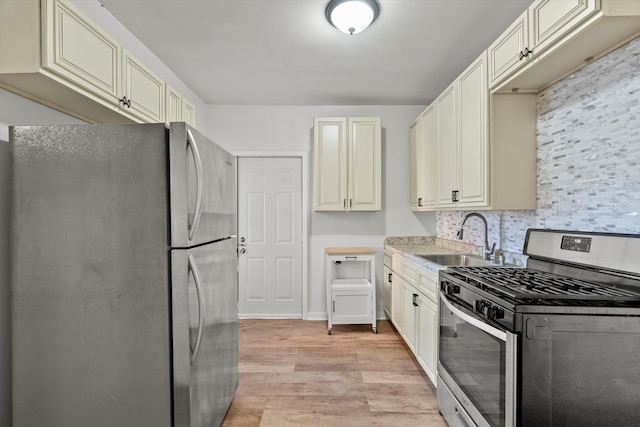 kitchen with light wood-type flooring, stainless steel appliances, sink, and cream cabinetry