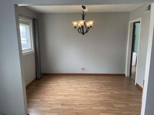 empty room with light hardwood / wood-style flooring and an inviting chandelier