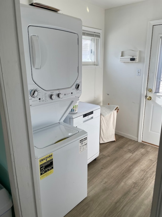 clothes washing area featuring hardwood / wood-style floors and stacked washer / drying machine