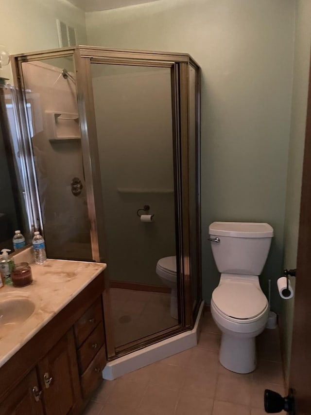 bathroom with tile patterned flooring, vanity, a shower with shower door, and toilet