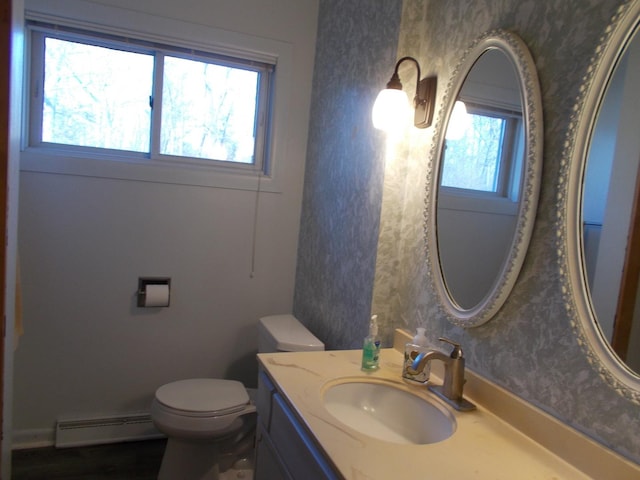 bathroom featuring vanity, a healthy amount of sunlight, toilet, and a baseboard radiator