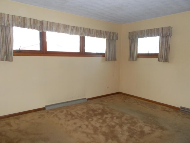 spare room with carpet flooring, a textured ceiling, and a baseboard radiator