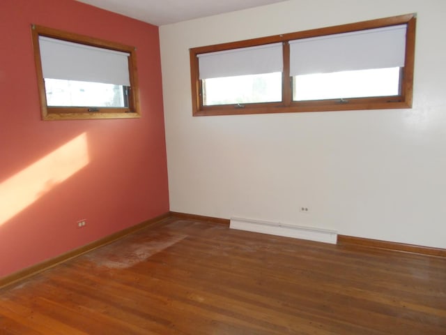 empty room with dark hardwood / wood-style flooring and a baseboard radiator