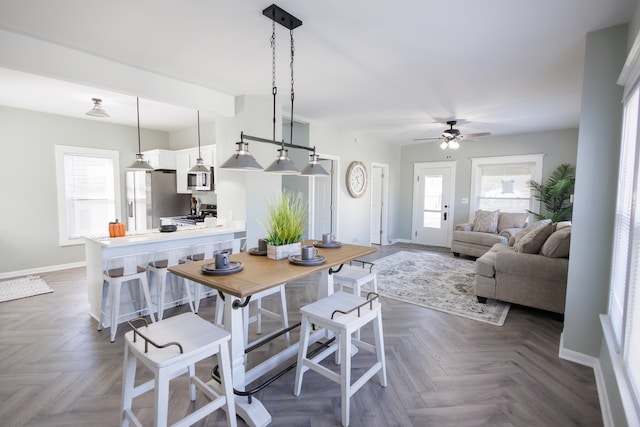 dining room with dark parquet flooring, a healthy amount of sunlight, and ceiling fan